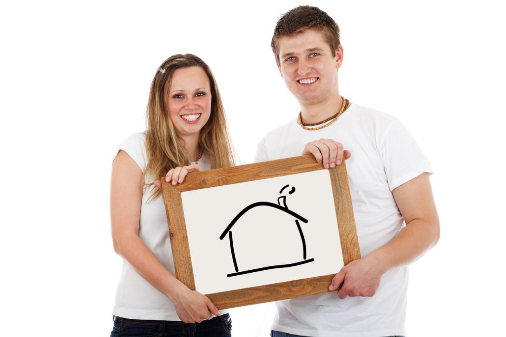 Couple holding a frame with home drawn on it