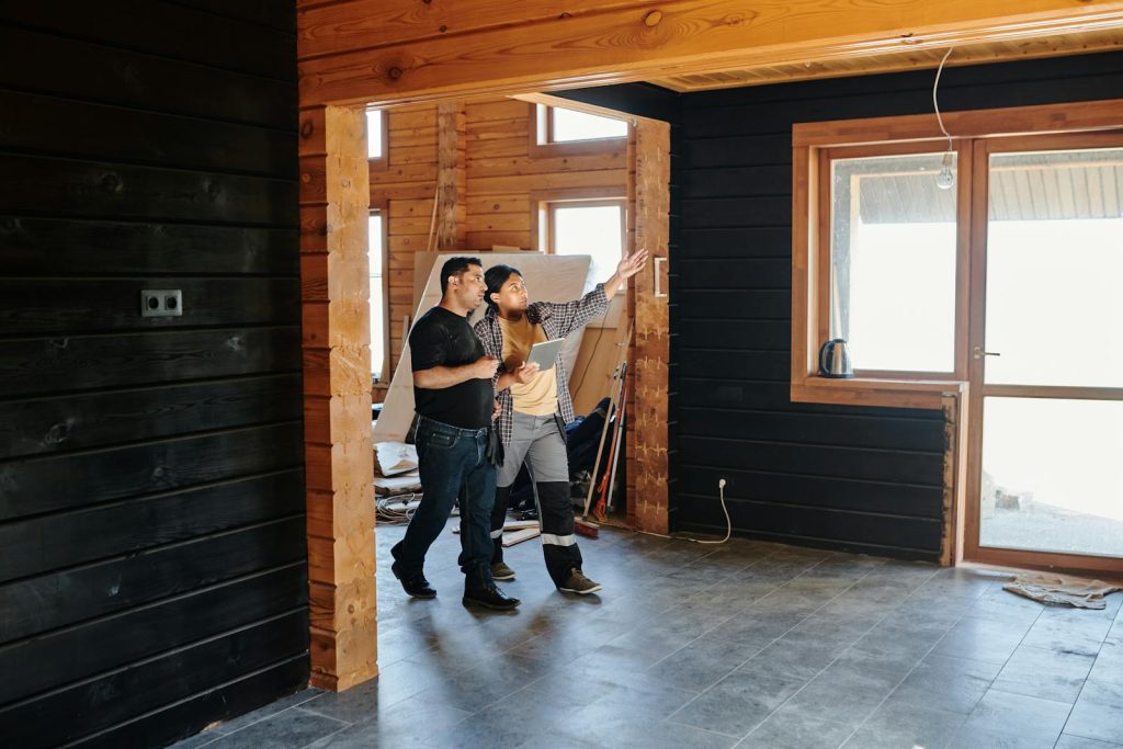 Two adults discussing home renovation in a partially constructed modern wooden interior